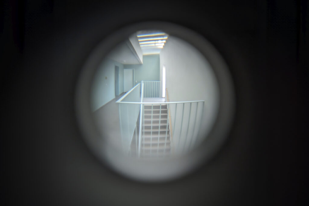Ein Blick durch einen Türspion in ein leeres Treppenhaus